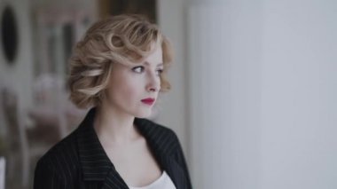 Lüks bir evde pencereden bakan düşünceli bir kadın.