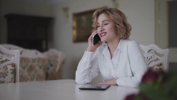 Donna felice che parla al telefono a tavola in casa luce di lusso — Video Stock