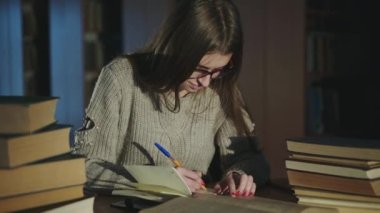 Gözlüklü kız daha sonra kütüphanedeki kitaplardan bilgi alır.