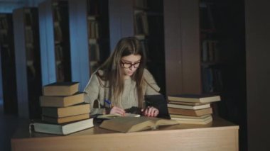 Çalışkan bir öğrenci kitaplardaki materyalleri not eder, parmaklarını çizgilere geçirir.