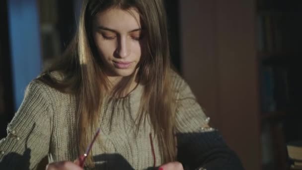 Schattig, jong meisje zet een bril op en glimlacht naar de camera in half-light bibliotheek — Stockvideo