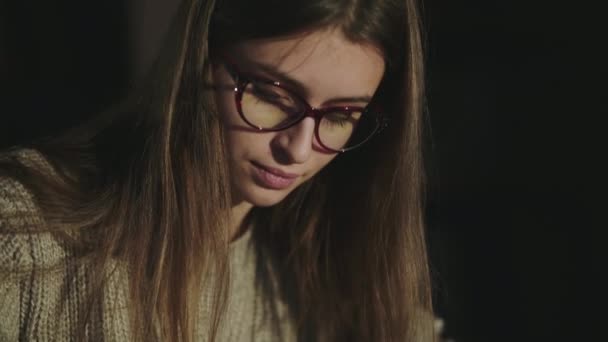 Portrait of pretty girl in glasses smiling at camera during writing with a pen — Stock Video