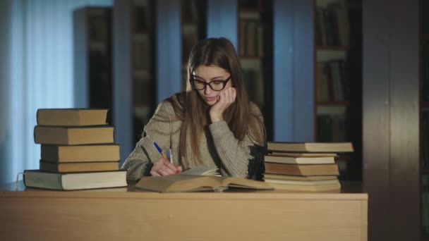 Ragazza in sorridere alla macchina fotografica e divertirsi durante la notazione di un compendio da libri — Video Stock