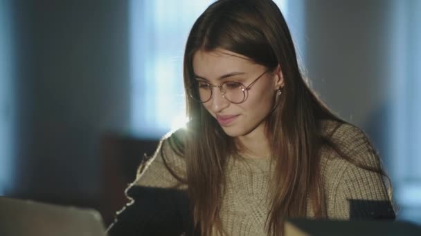 Sorrindo menina em óculos trabalhando com laptop dentro com backlit — Vídeo de Stock