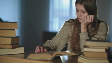 Yorgun öğrenci geç saatte kitap okuyor, masada uzanıyor ve uykuya dalıyor.