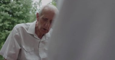 Üst düzey bir adam dışarıda arkadaşıyla satranç oynarken hamle yapıyor.