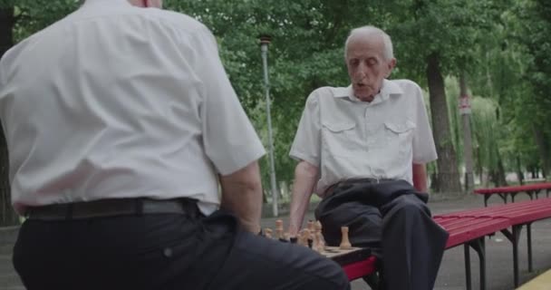 Dva senioři přátelé v oblecích mluvit během hraní šachové hry s radostí — Stock video