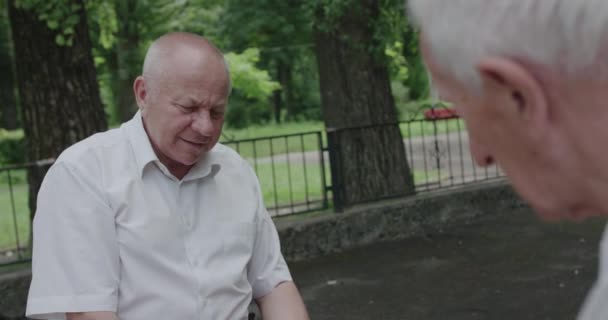 Amigos ancianos felices hablando y divirtiéndose durante un juego de ajedrez — Vídeo de stock