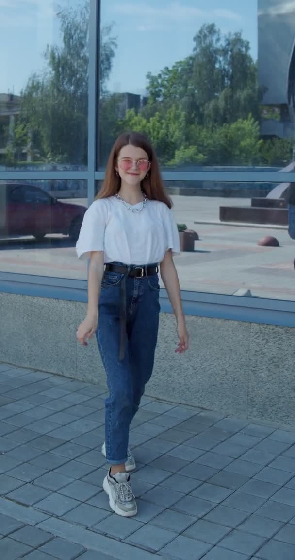 세련 된 아가씨가 현대식 유리 건물 밖에서 전면 카메라를 켜고 춤을 추고 있는 모습 — 비디오