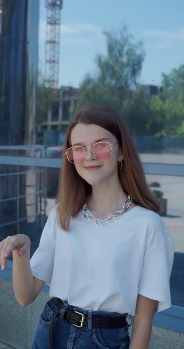 Portret van gelukkig jong meisje glimlachen op de camera en corrigeren stijlvolle zonnebril — Stockvideo