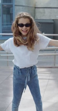 Şık görünümlü, dans eden ve kamerayla eğlenen mutlu küçük kız.