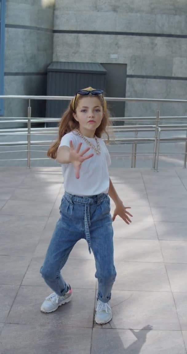 도시 지역에서 카메라 앞에서 힙합 춤을 추는 귀엽고 미소짓는 소녀 — 비디오