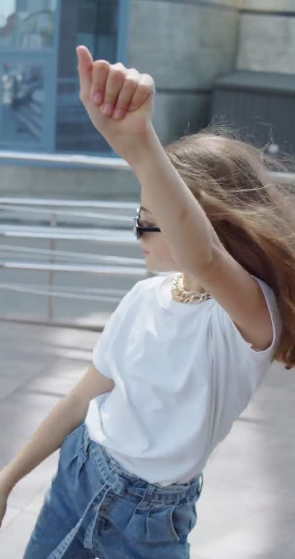Vedere atentă a fetiței în aspect elegant și ochelari care dansează pe zona urbană — Videoclip de stoc