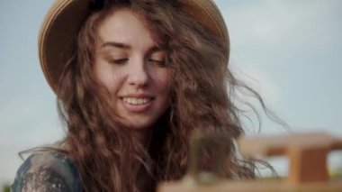 Güzel uzun saçlı ressamın portresi parlak gökyüzünde konuşuyor ve resim yapıyor.