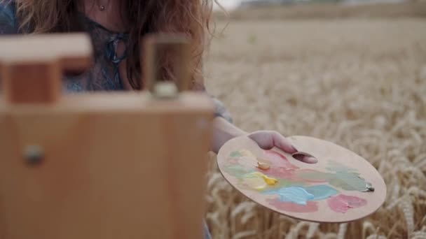 Vista de pintor detém uma paleta e tintas em tela entre trigo — Vídeo de Stock