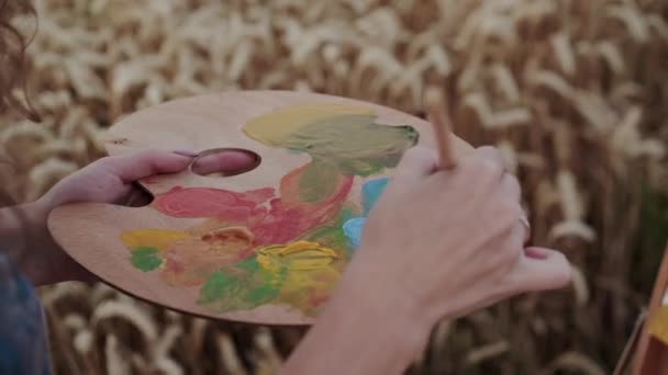 Vista de misturar uma aquarela na paleta de madeira com a mão feminina durante a pintura — Vídeo de Stock