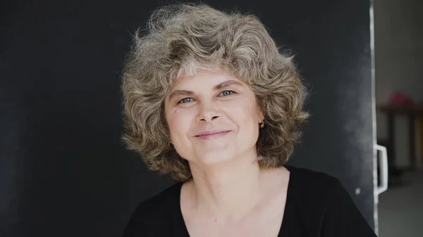 Portrait of mature woman smiling and talking thoughtfully aside camera Stock Photo