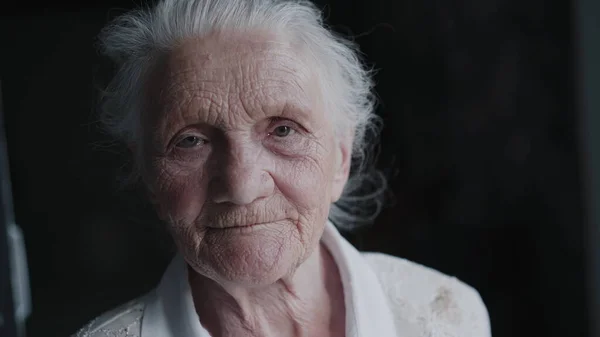 Ritratto di nonna dai capelli grigi con viso rugoso parla facile in macchina fotografica Foto Stock Royalty Free