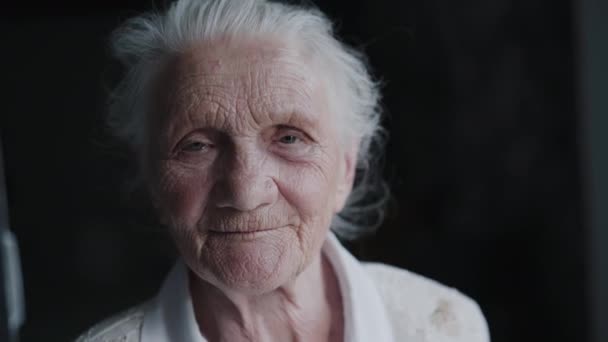 Kırışık yüzlü gri saçlı büyükannenin portresi kameraya kolayca yansıyor. — Stok video
