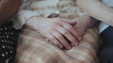 Yaşlı, bitkin kadın ellerini kameranın önünde birleştirmenin yakın görüntüsü