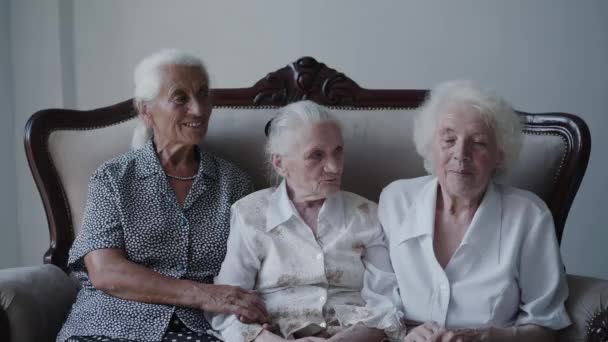 Portret van drie, gemengde ras grootmoeders zittend op de bank, emotioneel lachend — Stockvideo