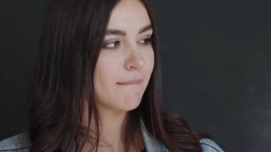 Güzel bir kızın portresi dudağını ısırır, aşağı bakar, konuşur ve kendine güvenerek yukarı bakar.