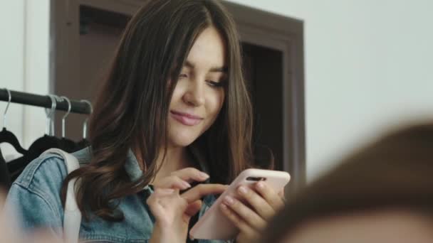 Modello grazioso utilizza smartphone nello spogliatoio durante il processo — Video Stock