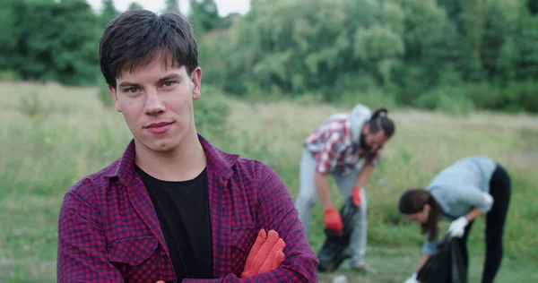 Man crosses hands, looks at camera on background of people collecting garbage Royalty Free Stock Images