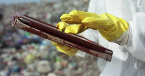 Close virologists hands in yellow gloves typing on a tablet at dump landfill — Stock Video