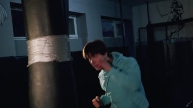 Yalnız boksör ağır çekimde kum torbasına vurur. Genç adam içeride antrenman yapıyor. Spor salonunda güçlü bir atlet. Spor konsepti.