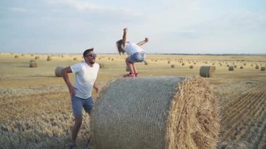 Küçük kız tarladaki koca bir samandan babasının kollarına atlıyor.