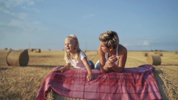 Famiglia felice che si rilassa su un pagliaio in una giornata di sole nel campo — Video Stock