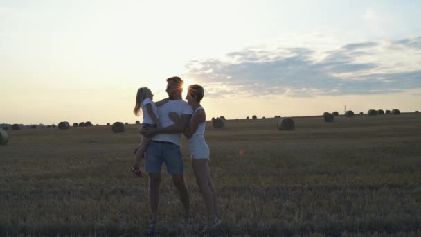 Retrato de familia feliz divirtiéndose con su hija en un campo — Vídeos de Stock