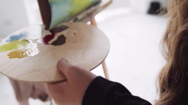 Kapalı alanda, ahşap ellerin, boya fırçası ve palet ile resim çizdiği, renkli boyalar..