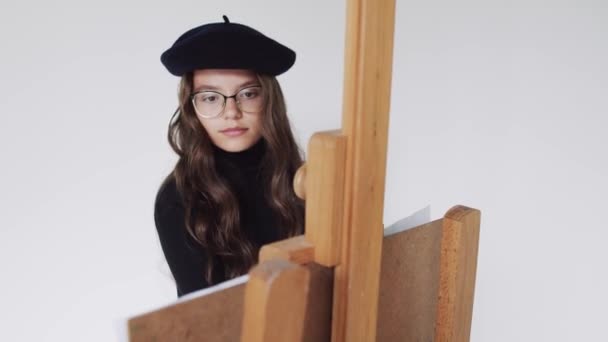 Молодая художница в беретовой картине на холсте в художественной студии — стоковое видео