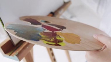 Kapalı alanda, ahşap ellerin, boya fırçası ve palet ile resim çizdiği, renkli boyalar..