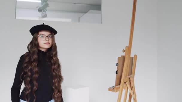 Portrait d'artiste heureuse femme posant près du chevalet avec toile et palette pendant le travail en regardant la caméra — Video