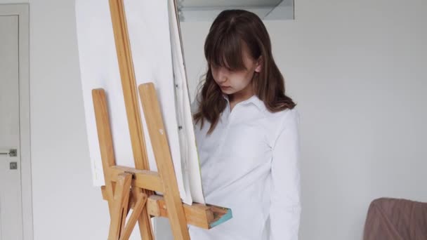 Junge Künstlerin malt Bild auf Leinwand im Kunstatelier — Stockvideo