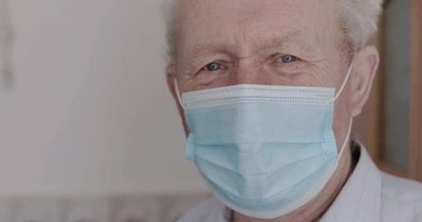 Portrait rapproché de grand-père avec masque regardant dans la caméra avec les yeux tristes intérieur — Video