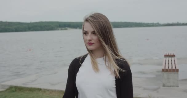Продумана дівчина з дме волоссям дивиться вбік на узбережжі — стокове відео