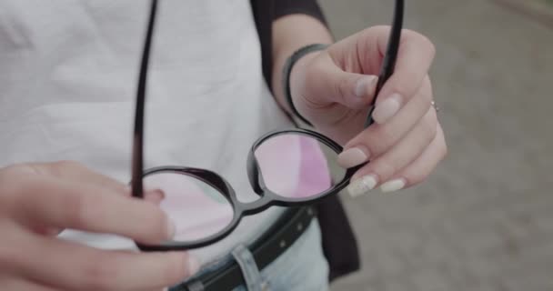 Utsikt över snygga glasögon i kvinnliga händer utomhus — Stockvideo