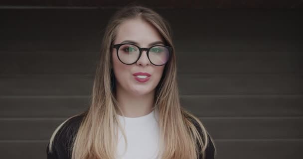 Stylish teenager with makeup in glasses inflates chewing gum into the camera — Stock Video