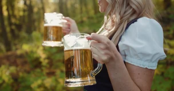 Rubia eslava se divierte, posa y hace clic en dos vasos de cerveza en el bosque de otoño — Vídeo de stock