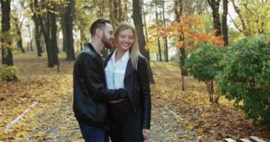 Mutlu çift kucaklaşır ve erkekler parkta kızların kulağına fısıldar.