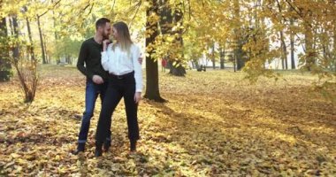 Güneşli sonbahar parkında durup birbirlerini okşayıp öperler.