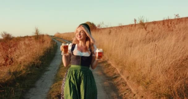 Speelse Slavische weelderige meisje in etnische jurk wandelingen met twee pinten bier en glimlacht — Stockvideo