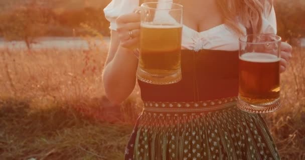 Mooie vrouw met weelderige borsten proost twee pinten van donker en licht bier — Stockvideo