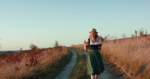 Meisje met twee pinten licht en donker bier loopt naar de camera en poseren op de natuur — Stockvideo