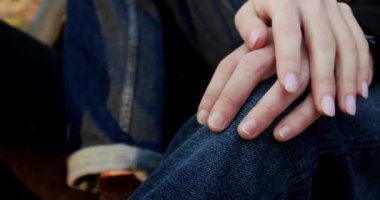 Kapalı kadın eli, dizine yaslanmış erkeği okşar.