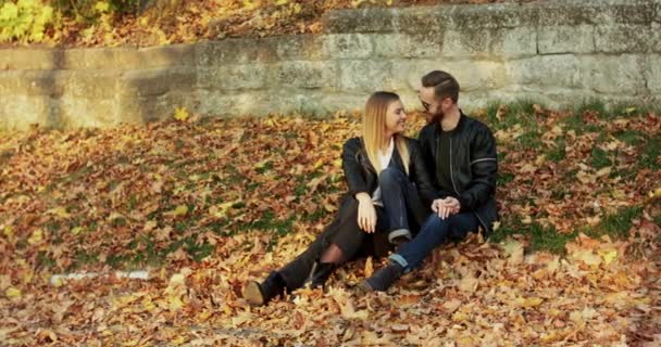 Mooi paar ontspannen op de herfst natuur in het park, ze glimlachen en kussen — Stockvideo